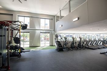 A gym with a row of exercise bikes and a weight training area.at Linc, Des Moines, 50309  